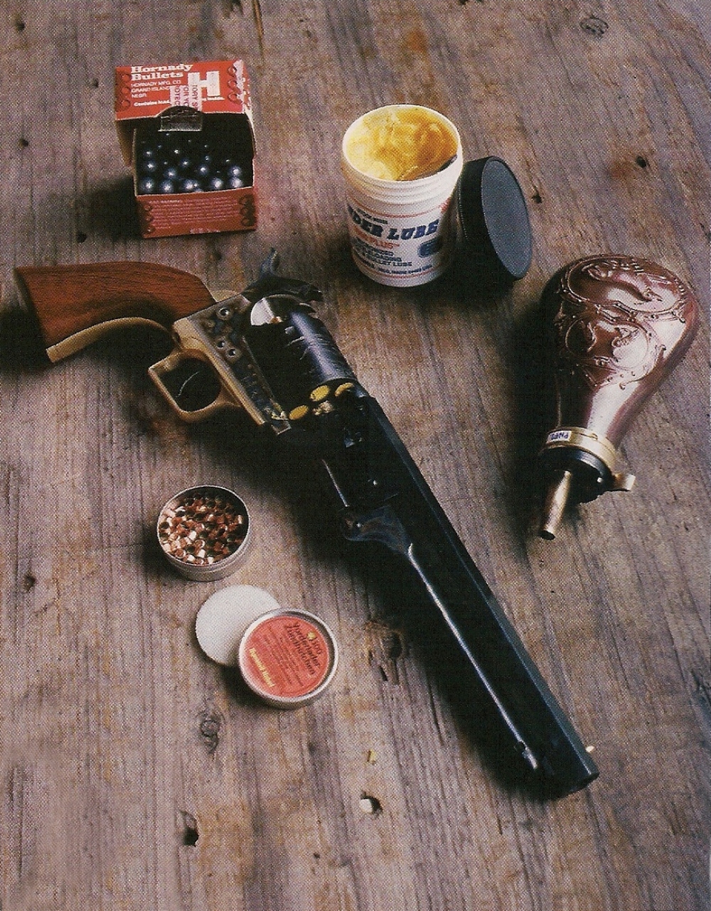 La réplique du Colt modèle 1851 Navy « Squareback », qui vient d'être chargée, est accompagnée des ingrédients indispensables à son utilisation au stand : poudre, balles, graisse et amorces.