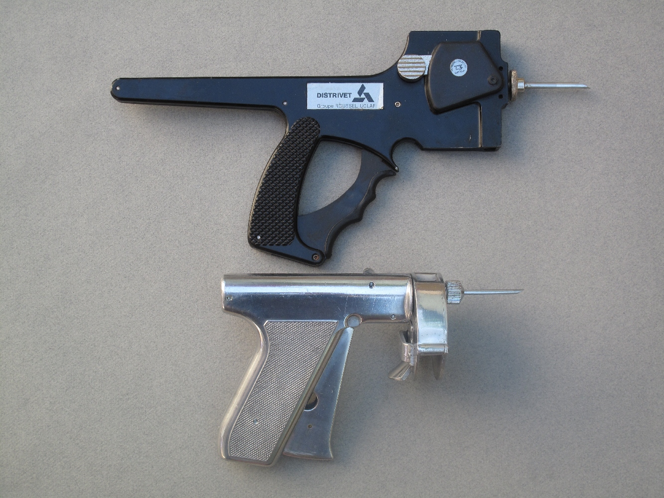 Voici deux anciens pistolets utilisés pour injecter des anabolisants (hormones de croissance) aux bovins. Celui du haut est un pistolet Distrivet, qui utilise un chargeur vertical de dix doses tandis que l’autre est un revolver RalOgun, qui se charge au moyen d’un barillet contenant vingt-quatre doses de produit.