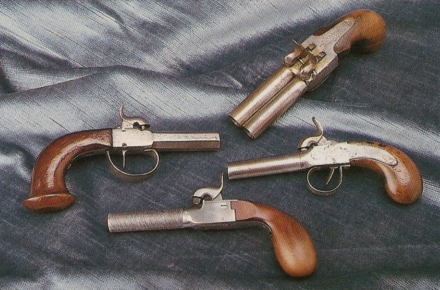 La réplique italienne est accompagnée ici par trois pistolets de poche anciens authentiques. Ces petits pistolets à coffre connurent un grand succès, comme arme de défense, de 1820 à 1860 environ, avant de céder progressivement leur place aux revolvers.