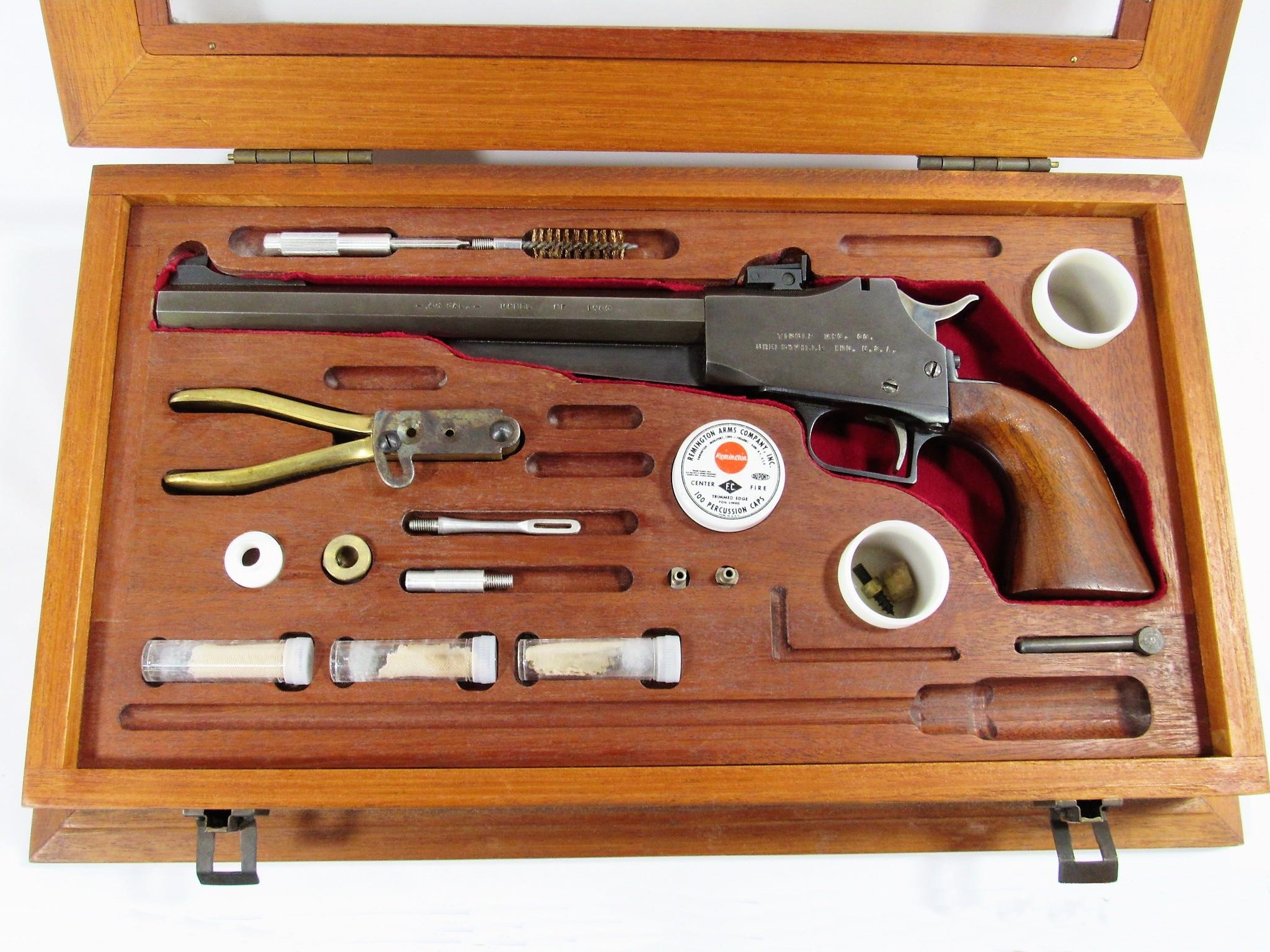 Présenté dans un coffret en bois et accompagné par ses accessoires, ce pistolet arbore le marquage « TINGLE MFG. CO. SHELBYVILLE IND. U.S.A. ». Il porte le numéro de série « 197 ».