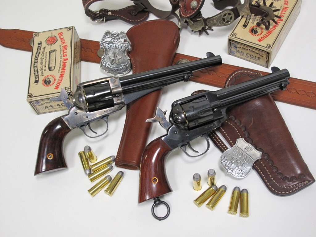 Les deux revolvers Remington Single Action Army modèle 1875 et modèle 1890 (répliques réalisées par la firme italienne Aldo Uberti) accompagnées de leurs munitions respectives (.44-40 WCF pour le premier et .45 Long Colt pour le second). Ils sont entourées de copies des accessoires d’époque : ceinturons, holsters, éperons, badges métalliques…