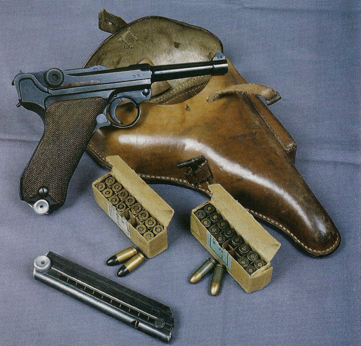 Modèle réglementaire allemand de la Seconde Guerre mondiale, ce P-08 fabriqué par Mauser en 1939 est accompagné par son holster en cuir et par deux boîtes de cartouches d'époque. 
